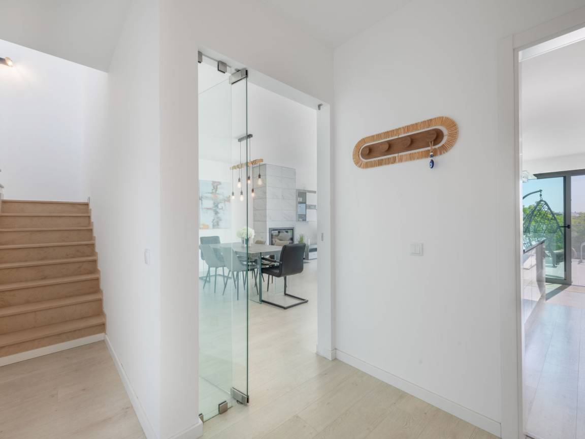 Entrée lumineuse avec escalier et porte vitrée vers le séjour