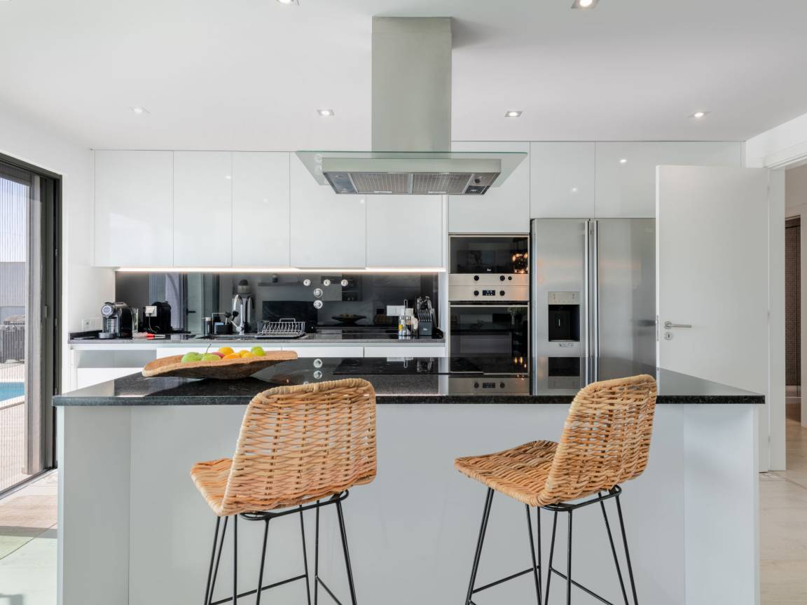 Îlot de cuisine avec tabourets en rotin et électroménager haut de gamme